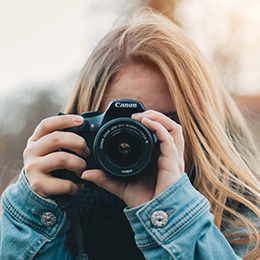 Girl holding and taking photos with a Canon camera photo by Christian Wiediger via Unsplash