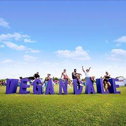 People sitting on a giant purple Vegandale sign photo courtesy Vegandale