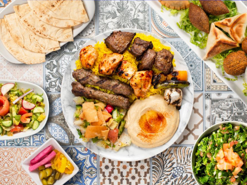 plate full of food surrounded by salads and bread