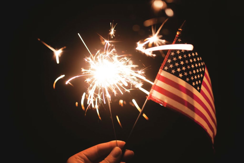 hand holding flag and sparkler